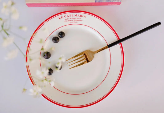 Top-down view of a white bone china quarter plate with double red circular borders and red "Le Cafe Maria" branding