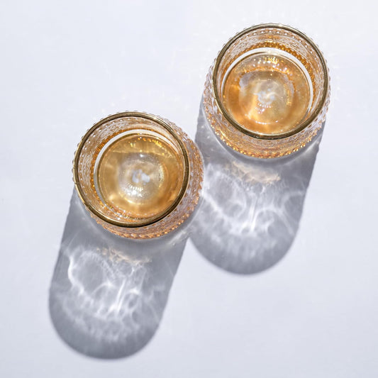 Top view of two crystal rotating whiskey glasses with gold rims and amber tint