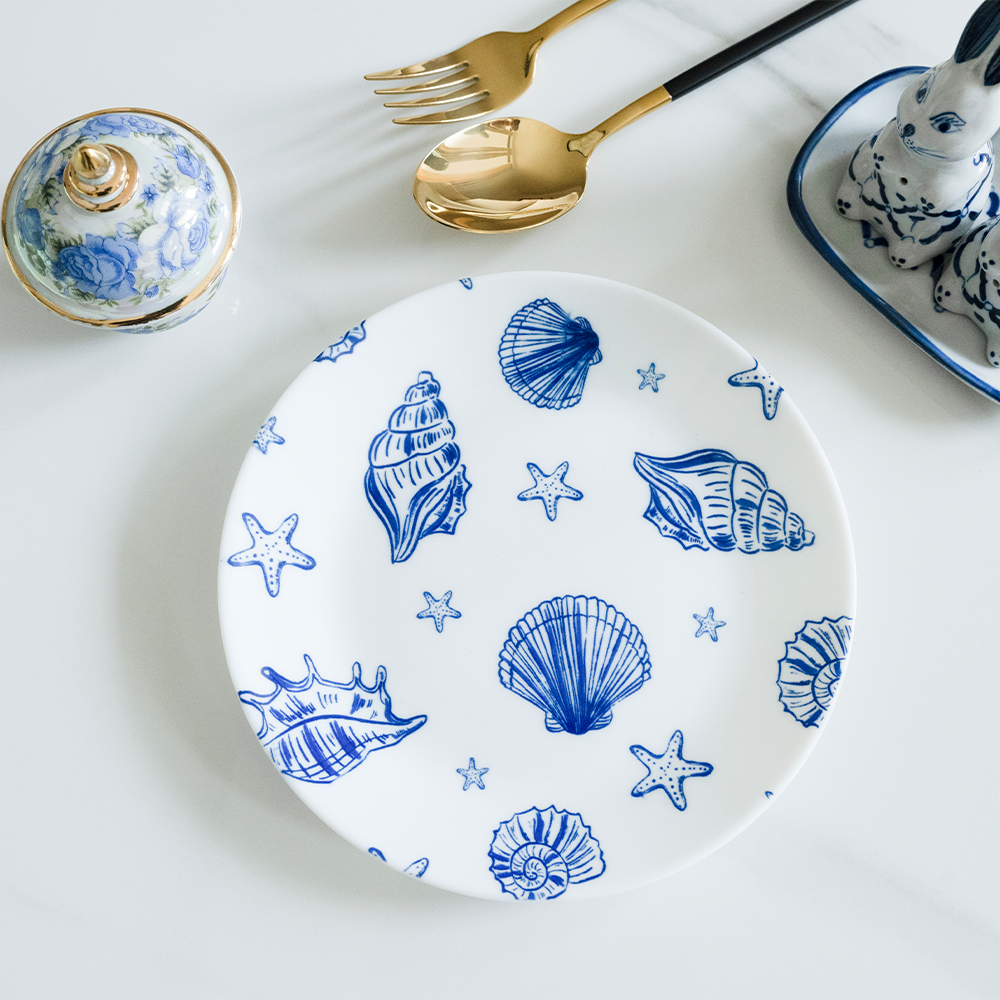 Bone china dinner plate featuring a blue nautical pattern with detailed seashells and starfish