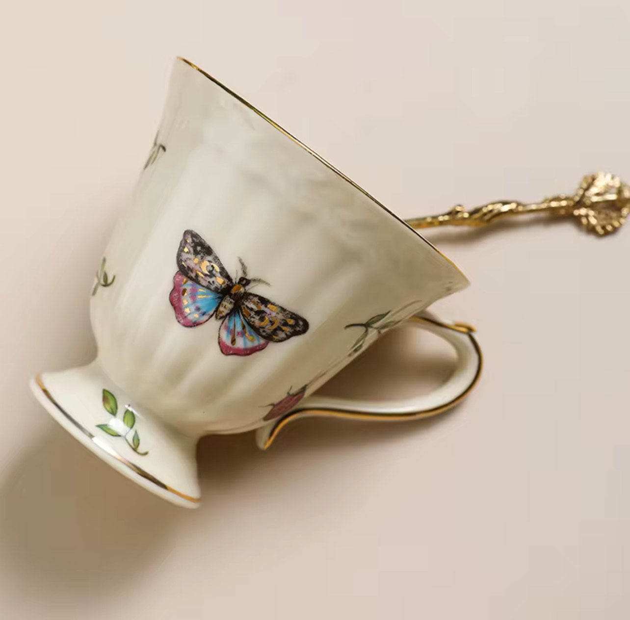 Bone china enchanted gardens cup with butterfly motif and gold spoon, close-up angled view
