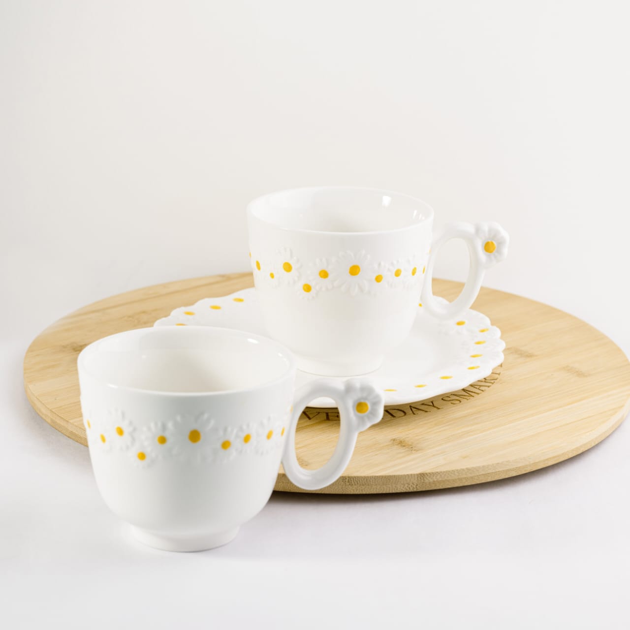 Set of two white bone china cappuccino mugs with embossed daisy patterns and flower handles on a neutral background