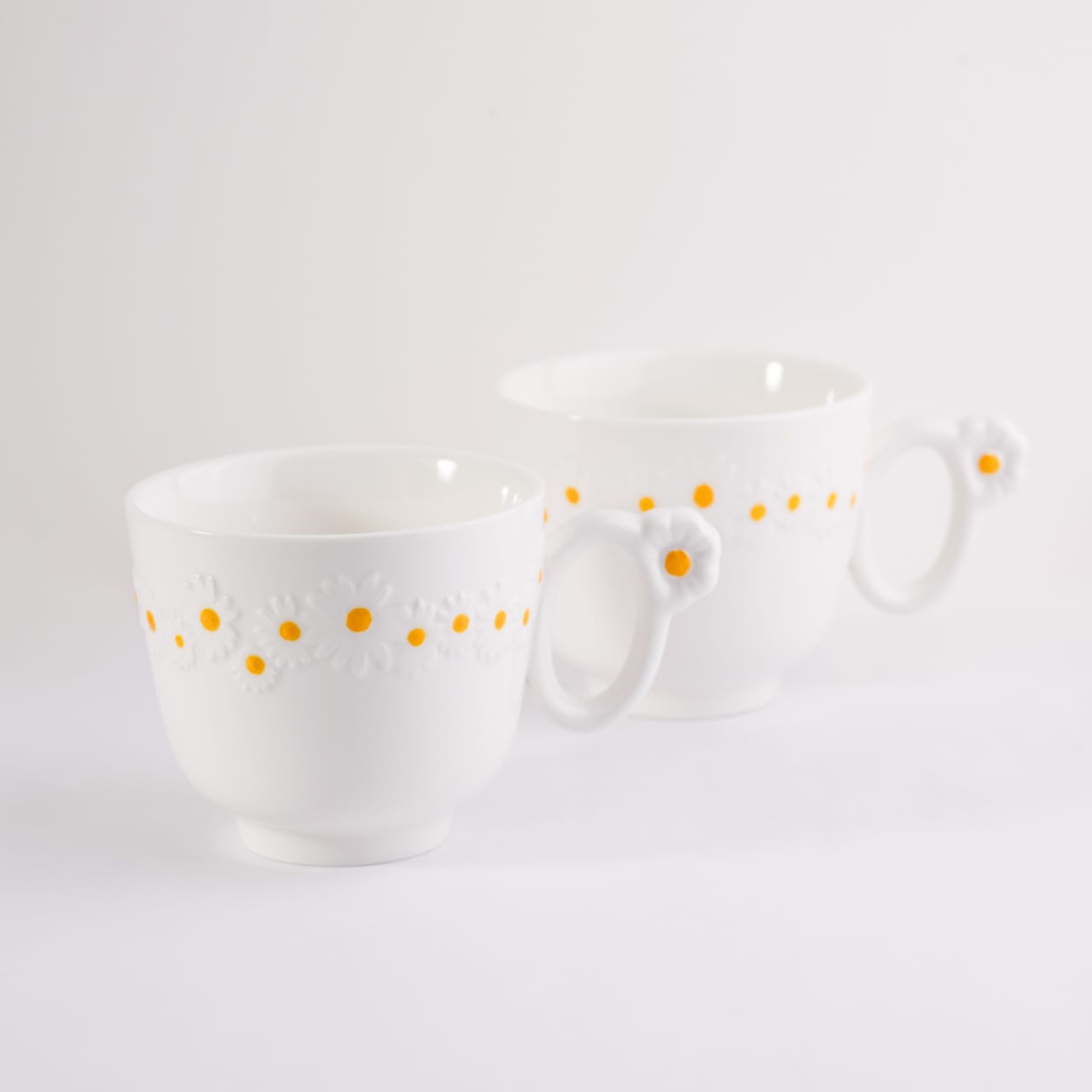 Set of two white bone china cappuccino mugs with embossed daisy patterns and flower handles