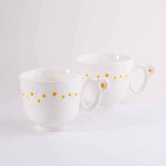 Set of two white bone china cappuccino mugs with embossed daisy patterns and flower handles