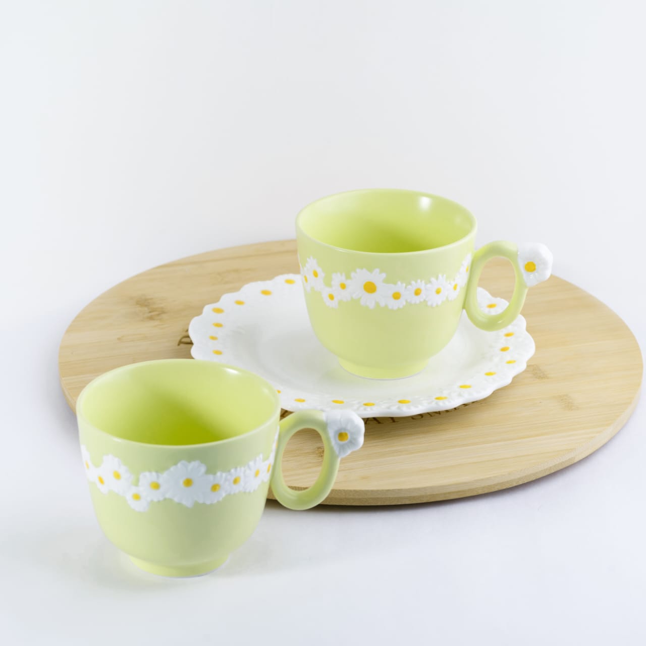 Set of two yellow bone china cappuccino mugs with embossed white daisy patterns and flower handles