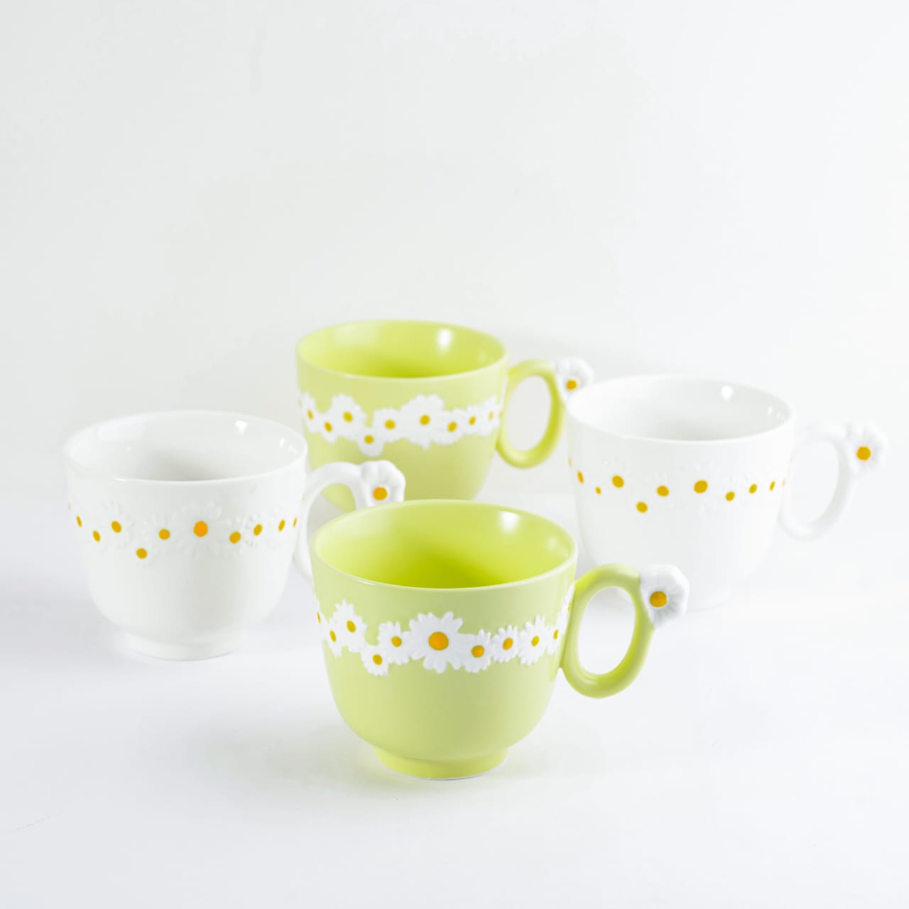 Group view of four bone china cappuccino mugs in yellow and white featuring embossed daisy patterns and flower-detailed handles