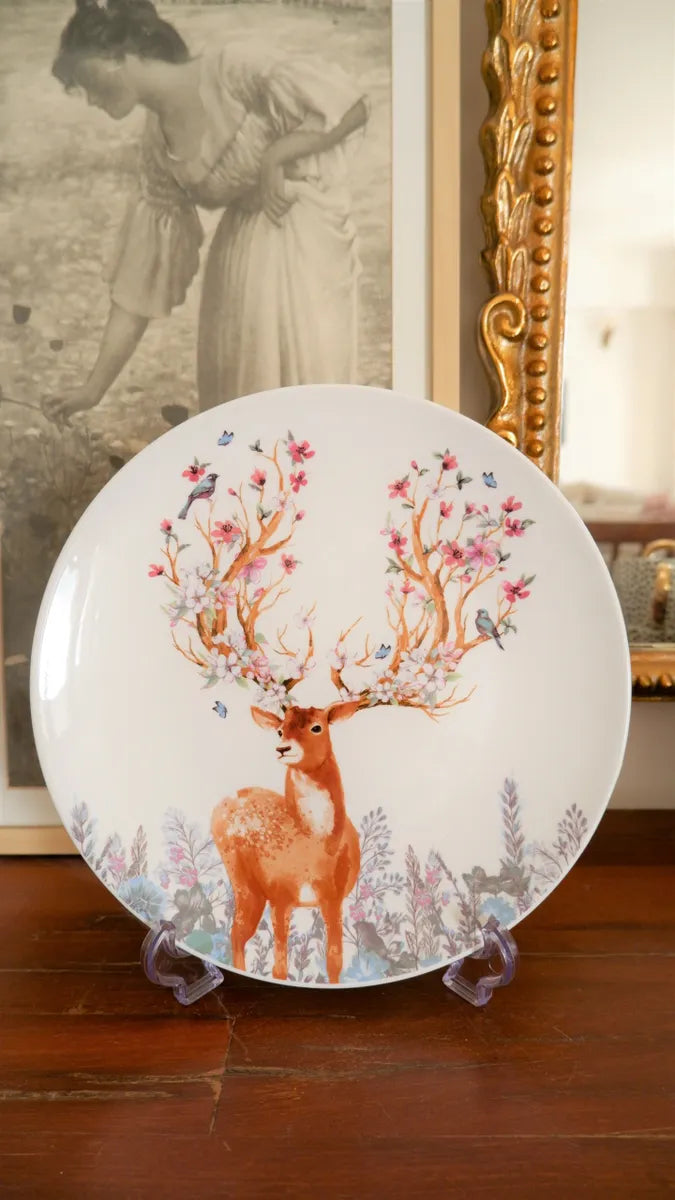 A large white bone china dinner plate featuring a vintage-style deer illustration with colorful floral antlers