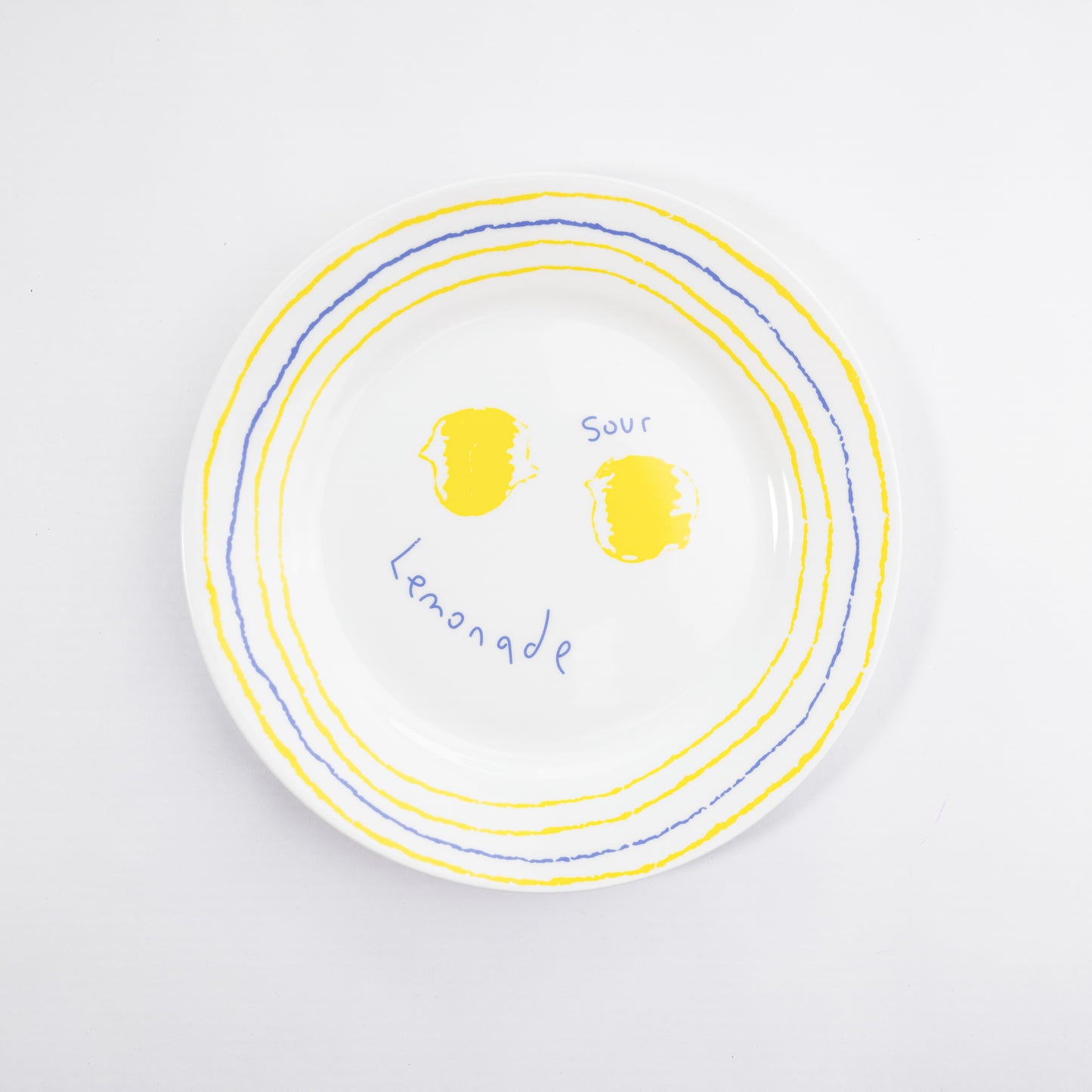 Top-down view of a white bone china quarter plate in the Lemonade style featuring yellow lemons and blue and yellow circular borders