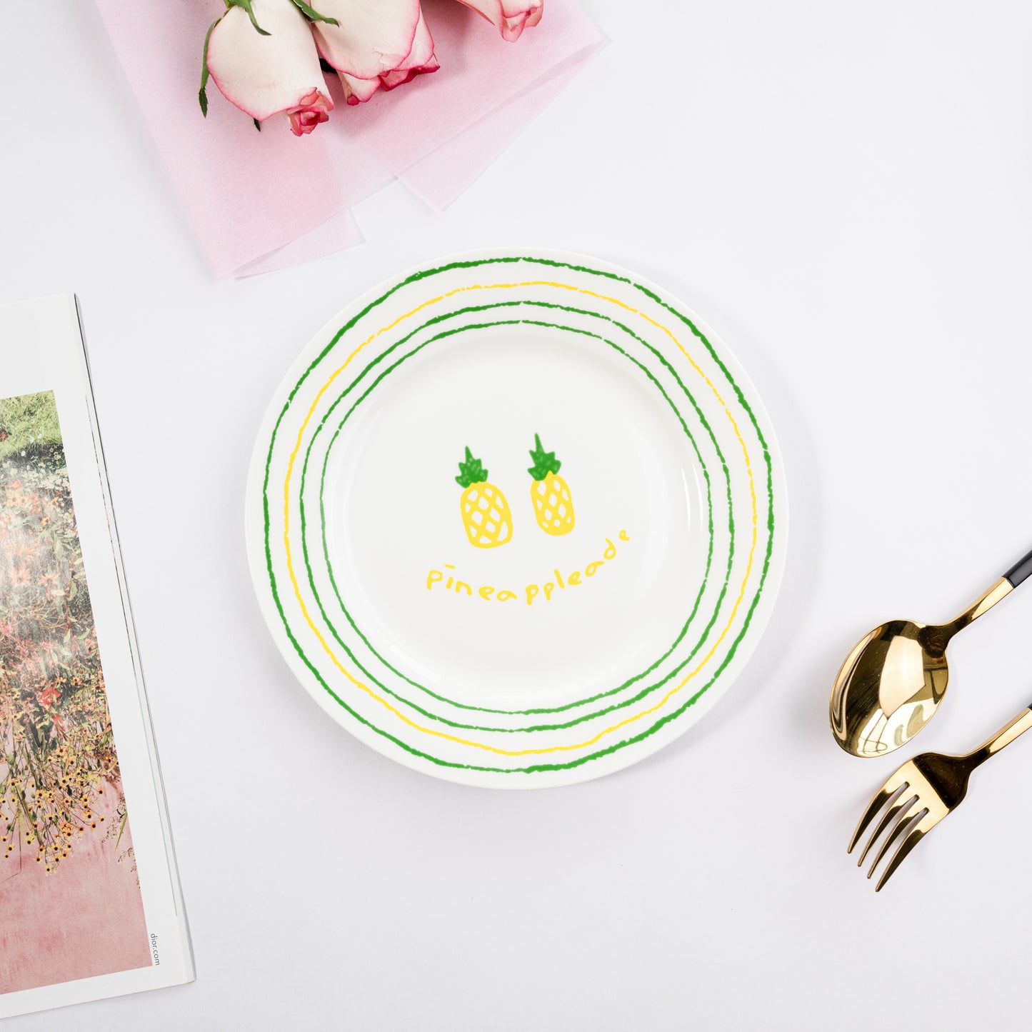 Top-down view of a white bone china quarter plate in the Pineappleade style featuring two yellow pineapples and green and yellow circular borders