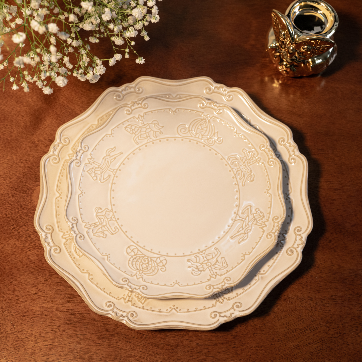 A top-down view of a matching 7-inch bone china quarter plate nested on top of a 10-inch dinner plate, both featuring detailed embossed carnival carousel horse and carriage carvings