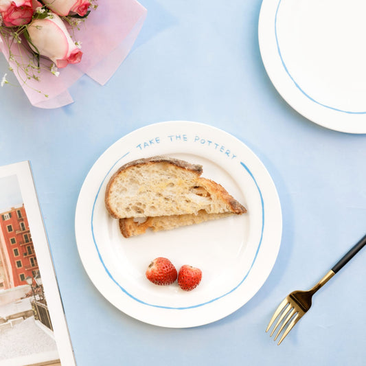 Minimalist white bone china plate featuring a blue rim and "TAKE THE POTTERY" text - Birdy Home Design