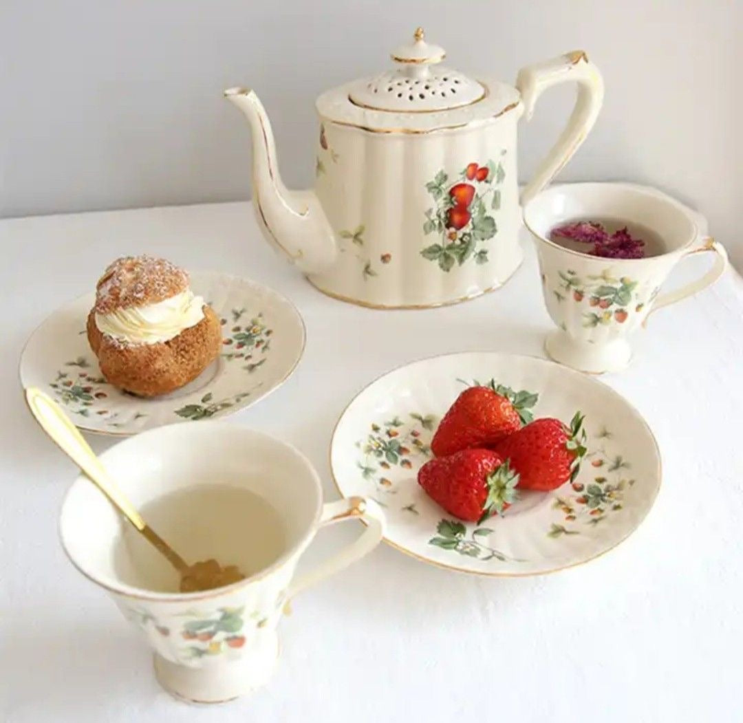 Bone china strawberries and cream teapot, two cups and two saucers with strawberry motif and gold rim.