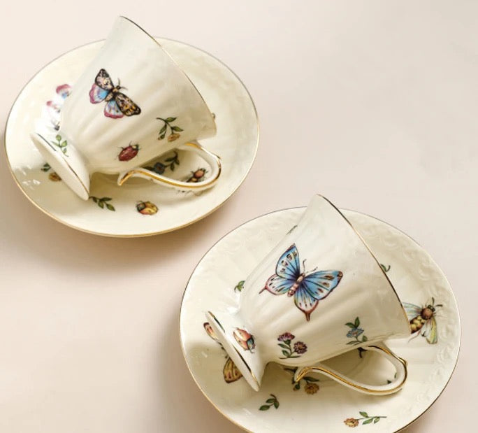 Bone china enchanted gardens two cups and saucers with different butterfly motifs and gold rim, top-down view