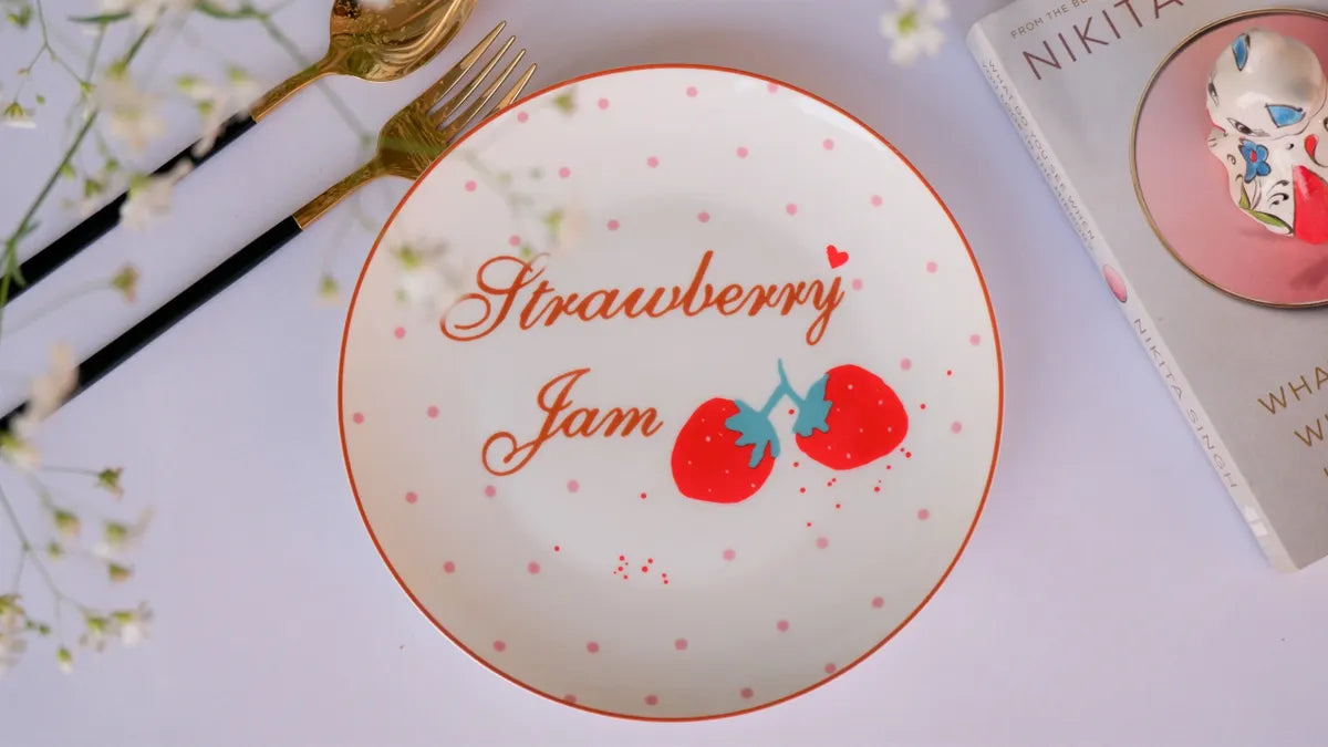 Close-up top-down view of an 8-inch white bone china plate with red "Strawberry Jam" text and strawberry illustrations