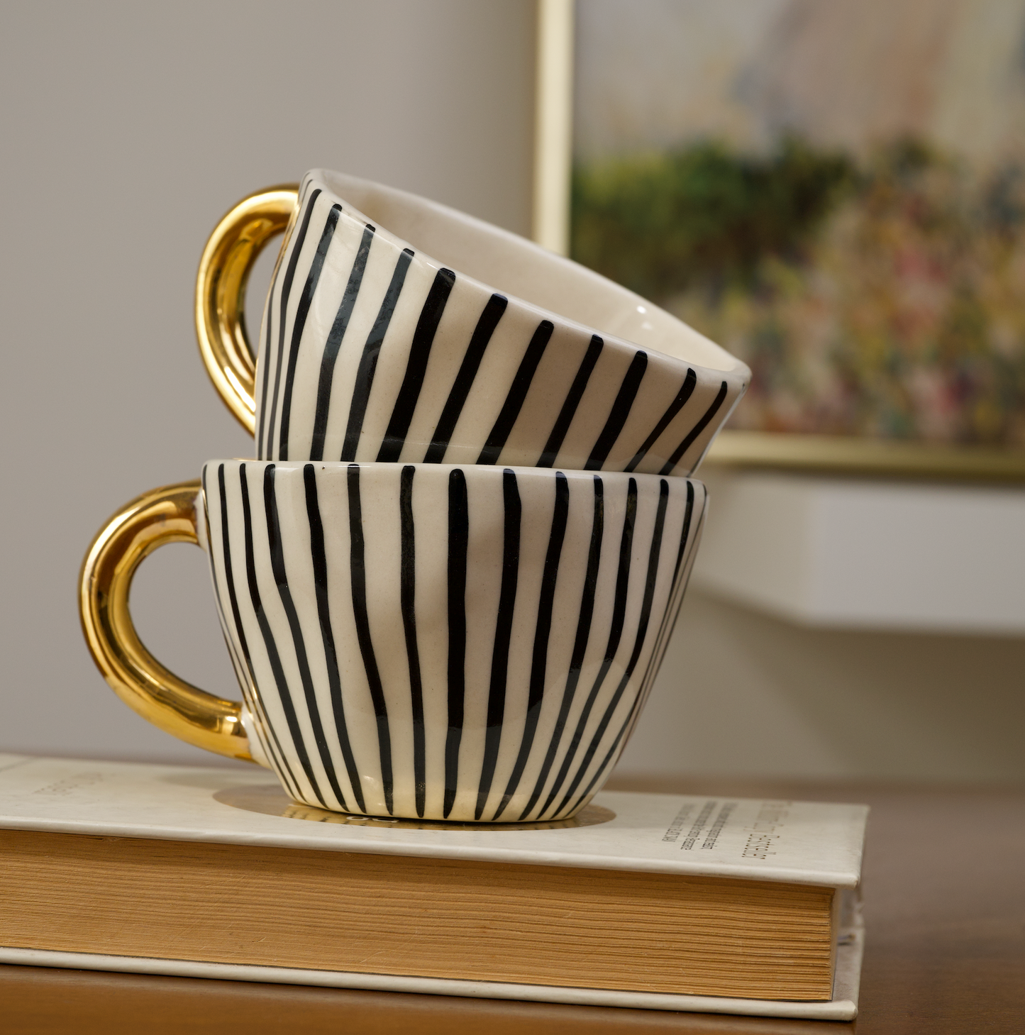 Stoneware mugs featuring black dotty, horizontal striped, and vertical striped patterns with gold handles