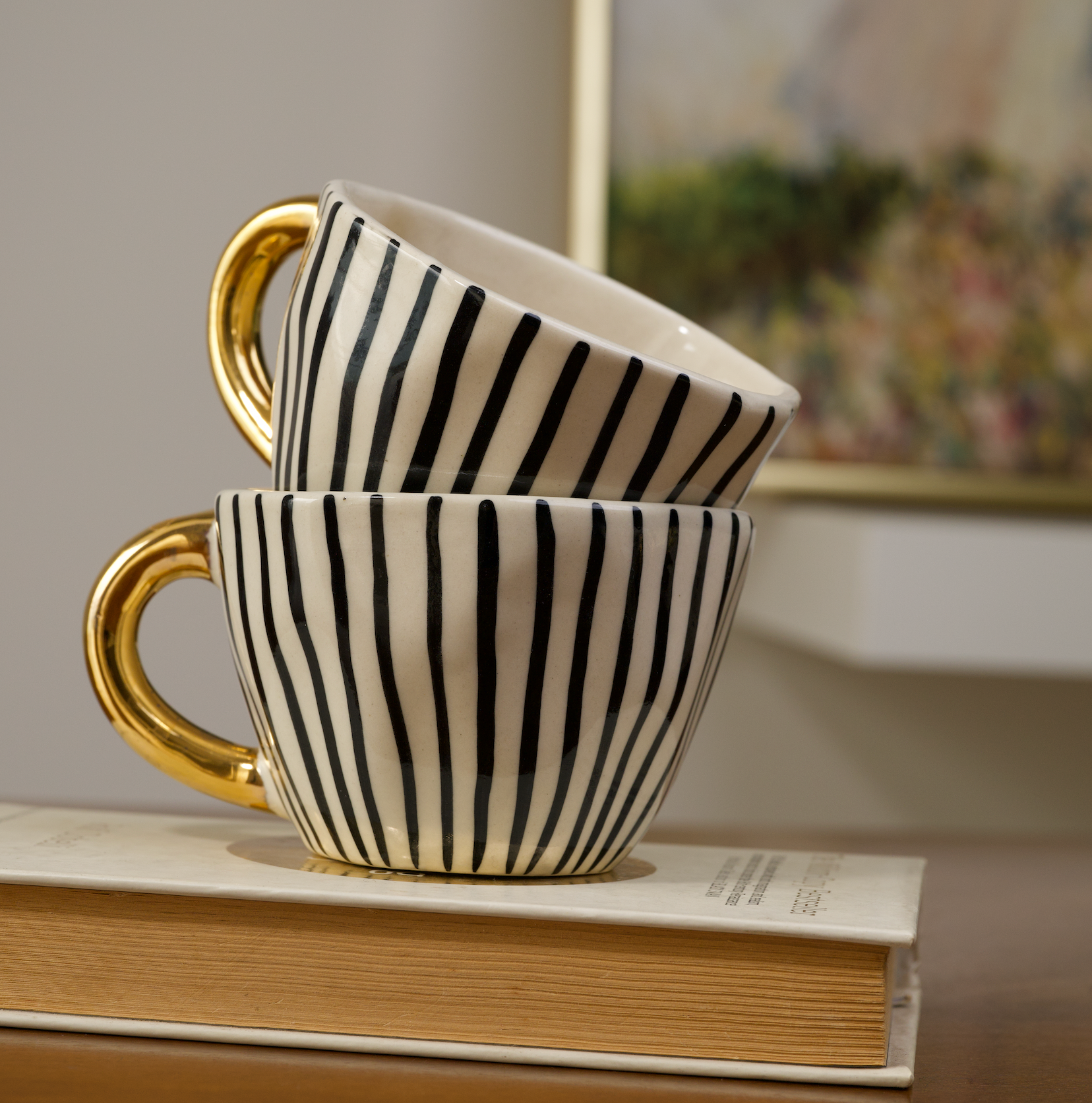 Stoneware mugs featuring black dotty, horizontal striped, and vertical striped patterns with gold handles