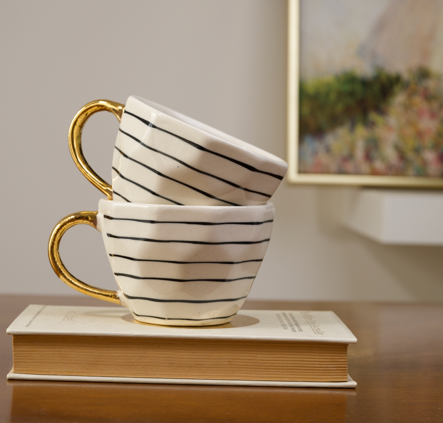 Stoneware mugs featuring a black horizontal striped pattern and gold handles stacked on each other - Birdy Home Design