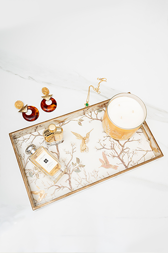 Top-down view of a rectangular white wooden tray with a gold border and gold chinoiserie bird and branch pattern